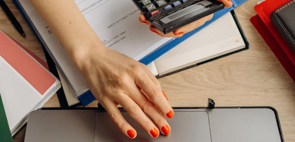 mujer calcula planillas usando calculadora y computadora